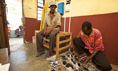 A Tanzanian man awaits the return of his mobile in a solar-powered phone charging booth