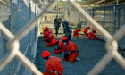 Detainees in orange jumpsuits sit in a holding area at Guantanamo Bay, Cuba
