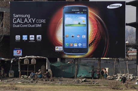 Afghan vendors sit under an advertising billboard in Kabul.