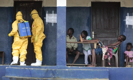 Members of an ambulance service disinfect a room in a village 30 miles north of Monrovia, Liberia.