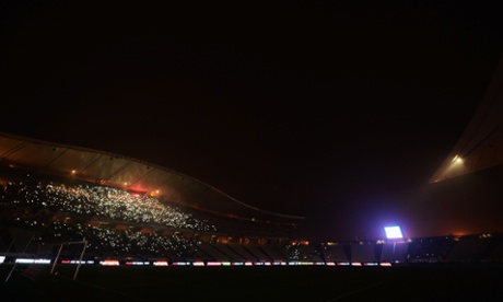 Fans shine lights from their mobile phones whilst play is suspended.