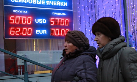 Muscovites pass a bureau de change. The rouble has sunk by more than 40% this year. 