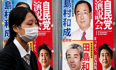 A woman walks past election posters for Japan's upcoming snap election in Tokyo, December 11, 2014.