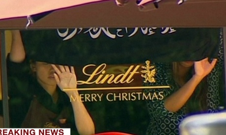 Hostages at the window of the cafe in Martin Place in Sydney holding a black and white flag believed to bear the Islamic creed.