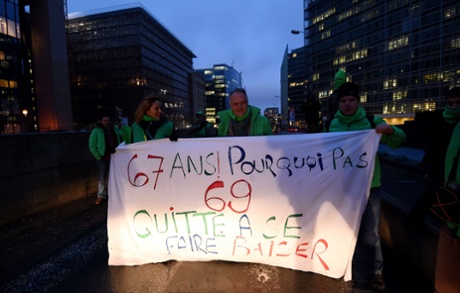 Belgian trade union members hold a banner reading 