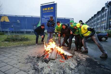 Belgian workers pose around a bonfire as they block access to an IKEA store in Sint Pieters Leeuw during a nationwide general strike on December 15, 2014.