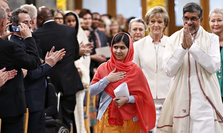 Nobel Peace Prize laureate Kailash Satyarthi walks, hands in prayer position, with Malala Yousafzai