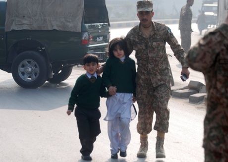 A soldier escorts schoolchildren after they were rescued from from the Army Public School that is under attack