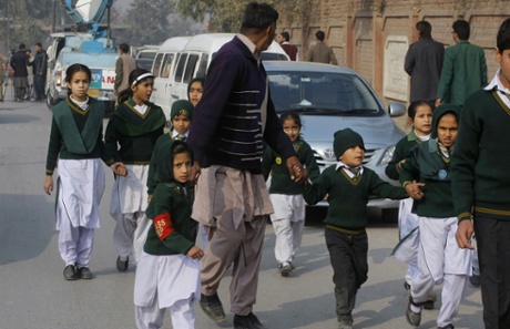 A plainclothes security officer escorts students rescued away from the school.
