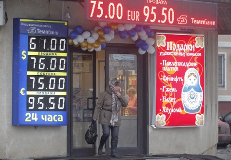 A woman walks in front of electronic information panels displaying currency exchange rates in Moscow, 17 December 2014.