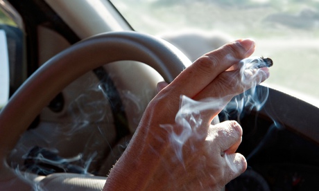 A woman holding a lit cigarette while driving
