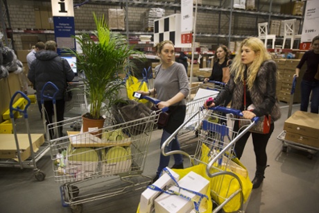 Women push carts with their purchases at the IKEA store on the outskirts of Moscow, Russia, Wednesday, Dec. 17, 2014.