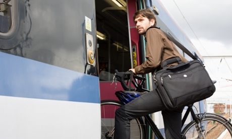 A man takes his bike onto a train.