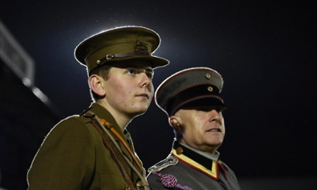 Two men wearing replica uniforms watch the football match between the British army and German forces at Aldershot Town FC.