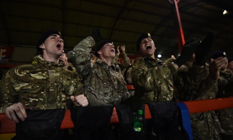 British army personnel celebrate the winning goal as they watch the commemorative football match.