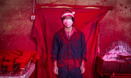 Santa's workshop … 19-year-old Wei works in a factory in Yiwu, China, coating polystyrene snowflakes with red powder.