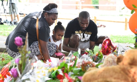 Members of the public lay flowers at a memorial in the park next the home of a multiple stabbing in the suburb of Manoora.