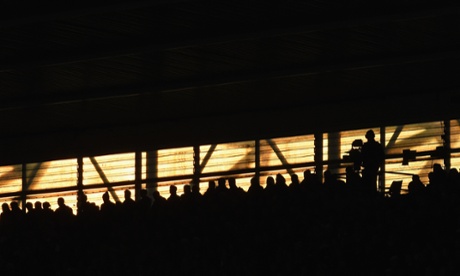 Fans, and a TV cameraman, watch the action as the sun sets at St Mary's Stadium in Southampton.