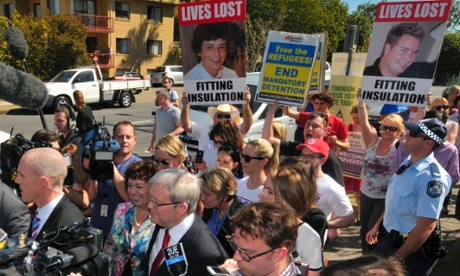 Kevin Rudd walks past protesters after casting his vote in Brisbane