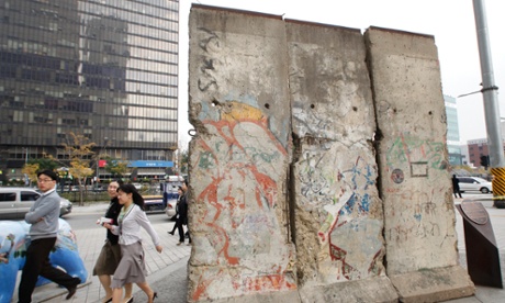 People walk past a section of the Berlin Wall displayed at Berlin Plaza in central Seoul.