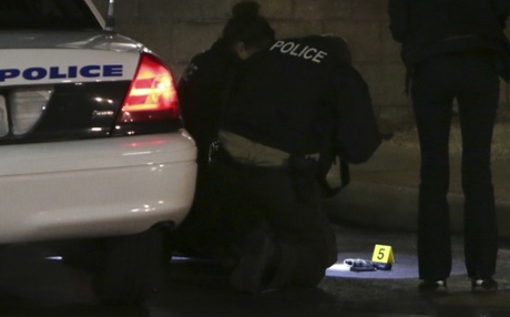 Police photograph a gun on the ground, following a shooting Tuesday at a gas station