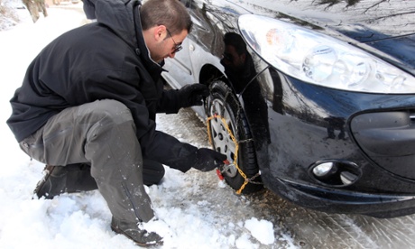 A man attaches snow chains after blizzards in the French Alps
