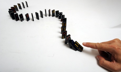 hand pushing over dominos 