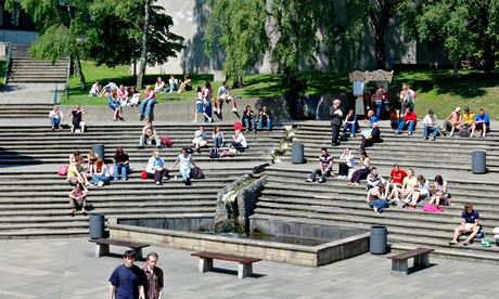 Students relaxing on steps in the sunshine on campus at the University of East Anglia