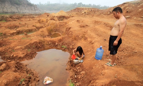 This picture taken on July 30, 2014 shows a girl and her father collecting water from an almost dried up resevoir, two kilometers from their home, in Pingdingshan, central China's Henan province. Severe drought and scorching heat has damaged over a million hectares of farmland in China's Henan and Inner Mongolia provinces, with no immediate relief in sight, a state news agency reported.
