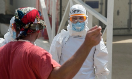 A foreign healthcare worker (R) waits for newly admitted Ebola patients at the British-run Save the Children Kerry Town Ebola treatment centre outside Freetown, Sierra Leone, on 22 December, 2014.