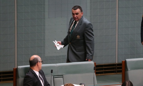 Attendants pick up a paper plane thrown from the public gallery.