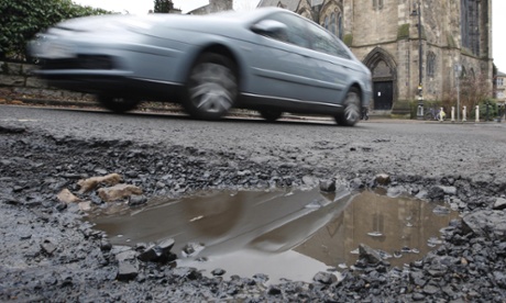 Car drives past a big pothole 