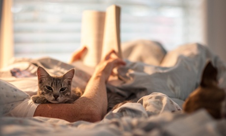 A man reading a book with his cat.
