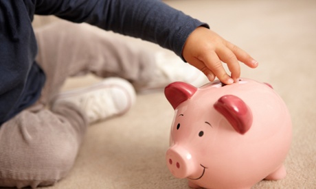 A little boy putting money into a piggy bank 
