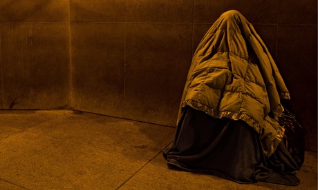 A homeless person covered in blankets 