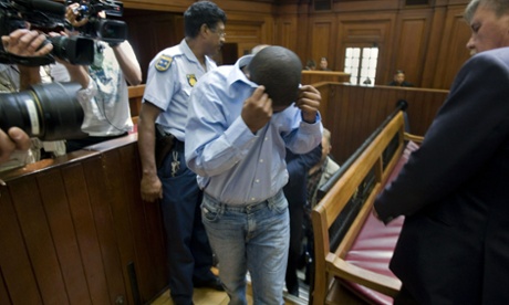 Zola Tongo (C), covers his face as policemen escort him to the Cape Town high court, in December 2010.