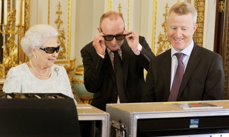 The Queen dons 3D glasses to view footage of her 2012 message with producer John McAndrew (centre) and director John Bennett.