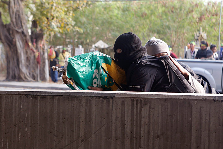 Bangkok Gunfight: An anti-government protester shoots his rifle in Bangkok