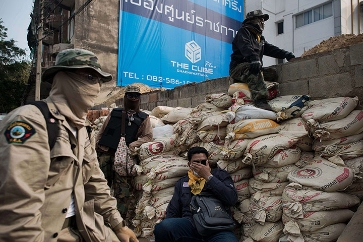 Bangkok Gunfight: Thai anti-government protesters secure an area outside a polling station