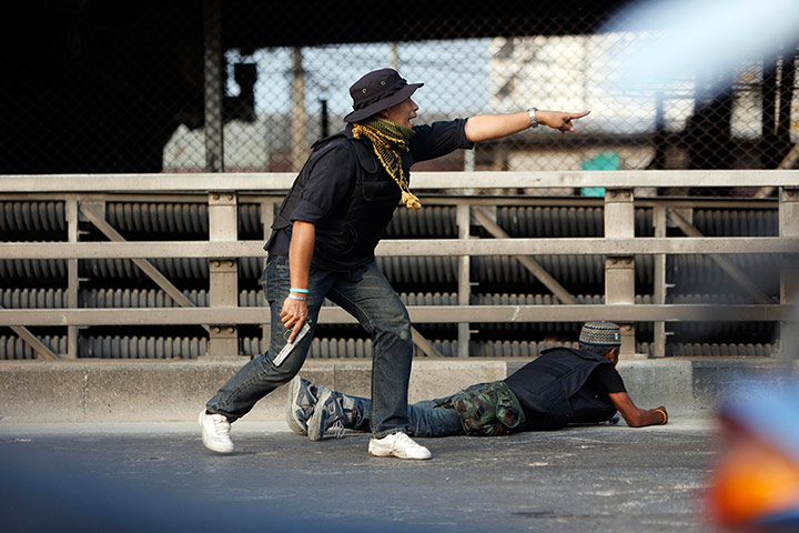 Bangkok Gunfight: An anti-government protester shouts before shooting his pistol in Bangkok