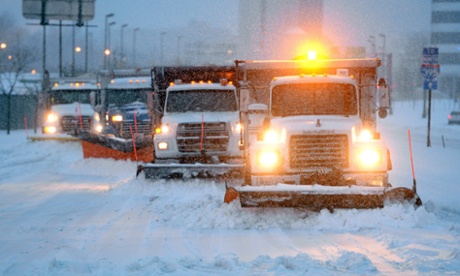Four trucks plow snow on a major road during a snowstorm in Arlington, Virginia.