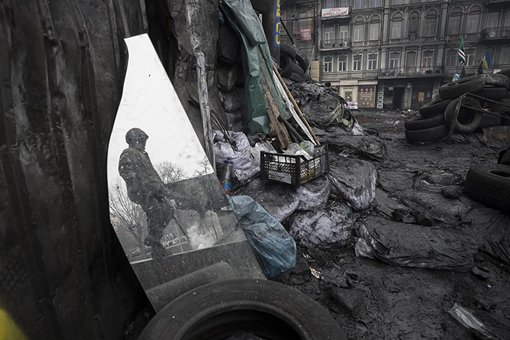 20 Photos: An anti-government protester is reflected in a mirror in Kiev