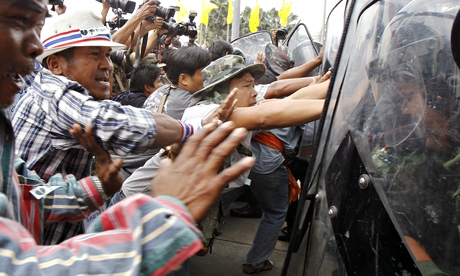 Farmers push against riot police during a protest in Bangkok