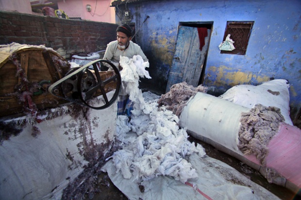 Ένας Ινδός εργαζόμενος επεξεργάζεται το βαμβάκι για τα παπλώματα σε ένα εργοστάσιο στα προάστια του Τζαμού, Ινδία.