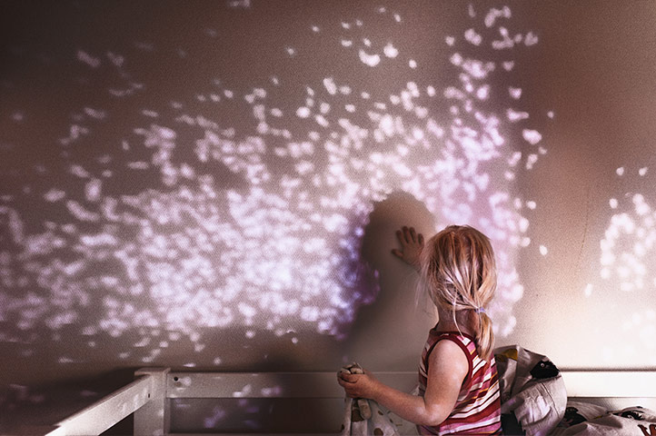 Big Pic - Down's Syndrome: little girl with back to camera looking at light on wall