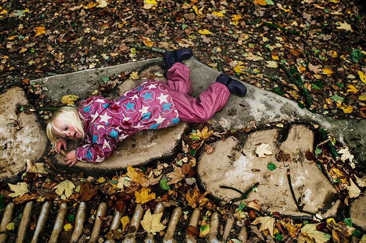 Big Pic - Down's Syndrome: little girl in pink jacket lying on ground with leaves