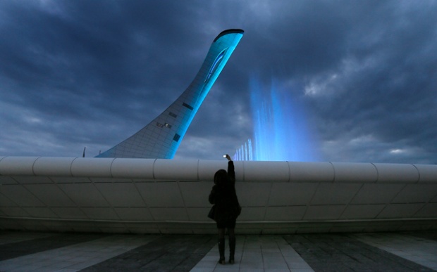 A woman takes photographs of a fountain at the base of the Olympic cauldron as preparations continue at the Olympic Park for the Sochi 2014 Winter Olympics.