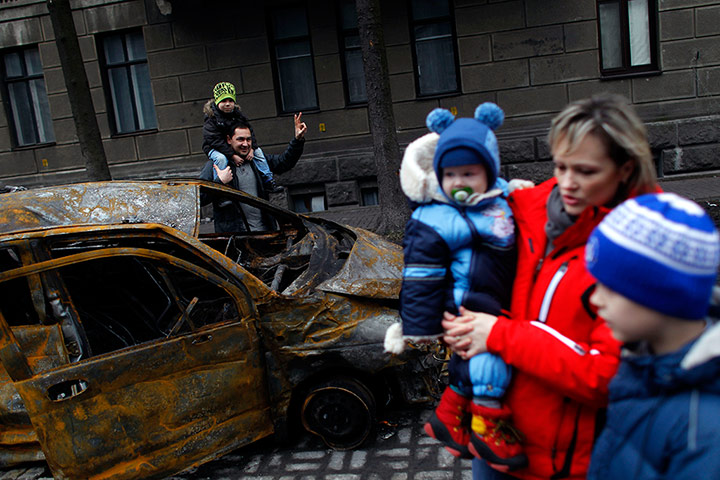kiev protests: People pass by a burned car in central Kiev