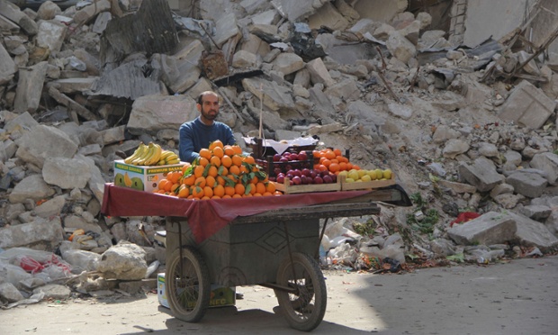 A Syrian fruit vendor waits for customers next to the ruins of a building in Aleppo.