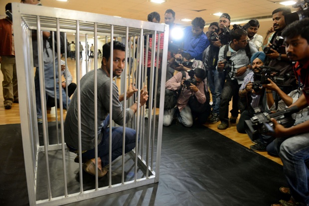 Members of the media take photographs as Indian cricketer Pragyan Ojha poses inside a cage during The People for the Ethical Treatment of Animals (PETA) shoot to protest zoo cruelty in Hyderabad.